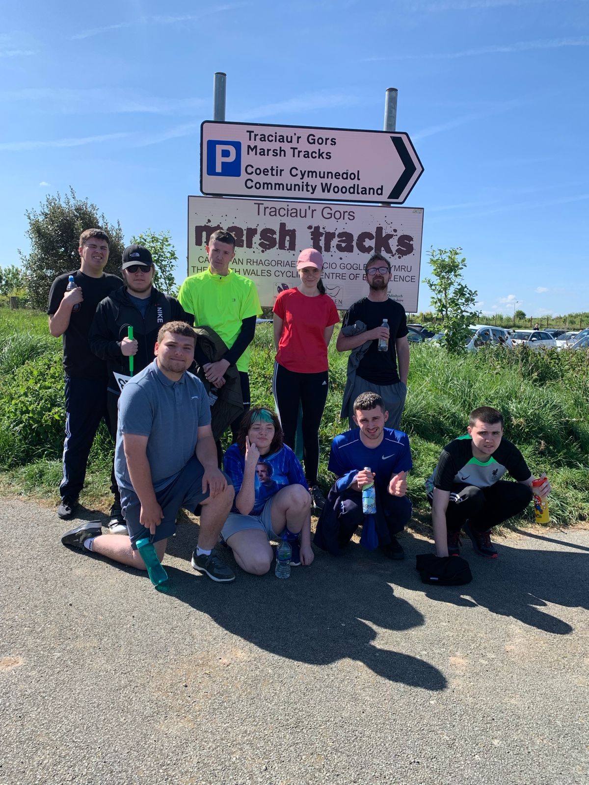 A group of hikers posing for a photo in front of a road sign
